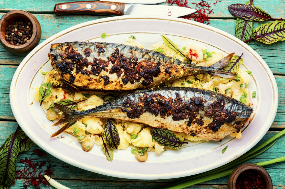 Appetizing roasted mackerel with boiled potatoes and herbs.. Baked whole scomber with potatoes