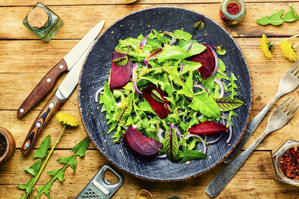 Fresh dandelion, sorrel and beetroot salad on rustic wooden table.Healthy eating,spring mix. Spring greens and beetroot salad