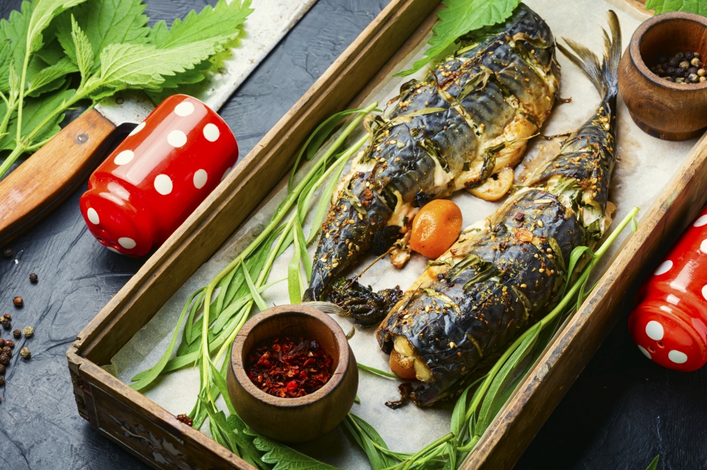 Roasted mackerel with tarragon and nettle.Grilled scomber in herbs on a wooden tray. Baked mackerel with herbs