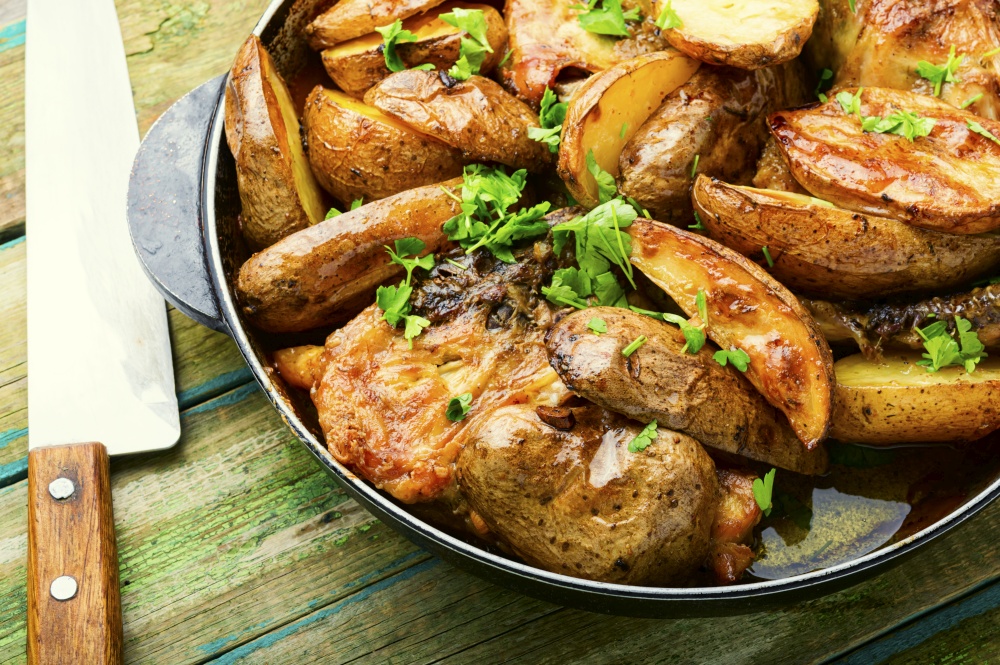 Delicious chicken meat with potatoes fried in a pan. Chicken baked with potatoes in a pan