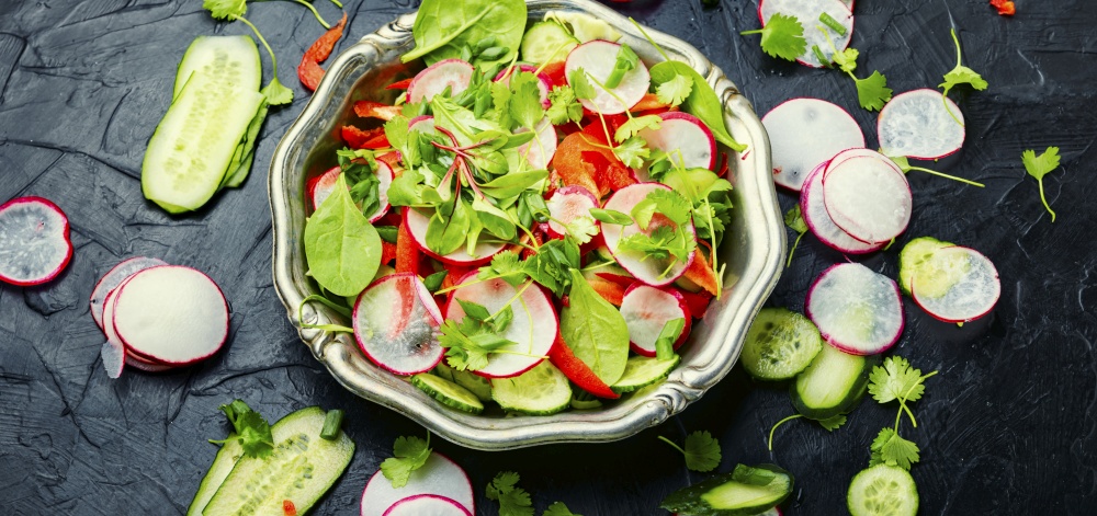 Healthy vegetable salad made from radish,pepper,cabbage and greens. Summer vitamin salad on a metal plate