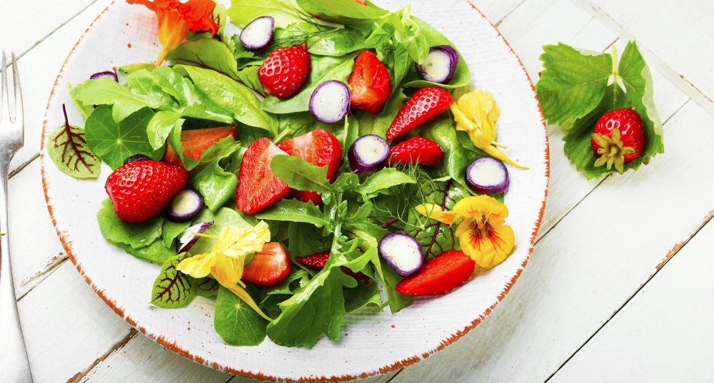 Vitamin salad with strawberries,spinach,nasturtium and arugula.Colorful summer salad. Summer salad with berries and green