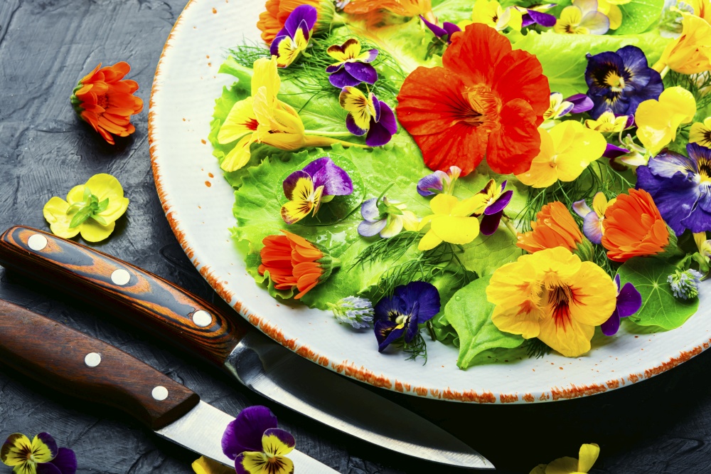 Healthy salad with green lettuce and edible flowers.Fresh summer salad with flowers. Edible flower salad in the plate