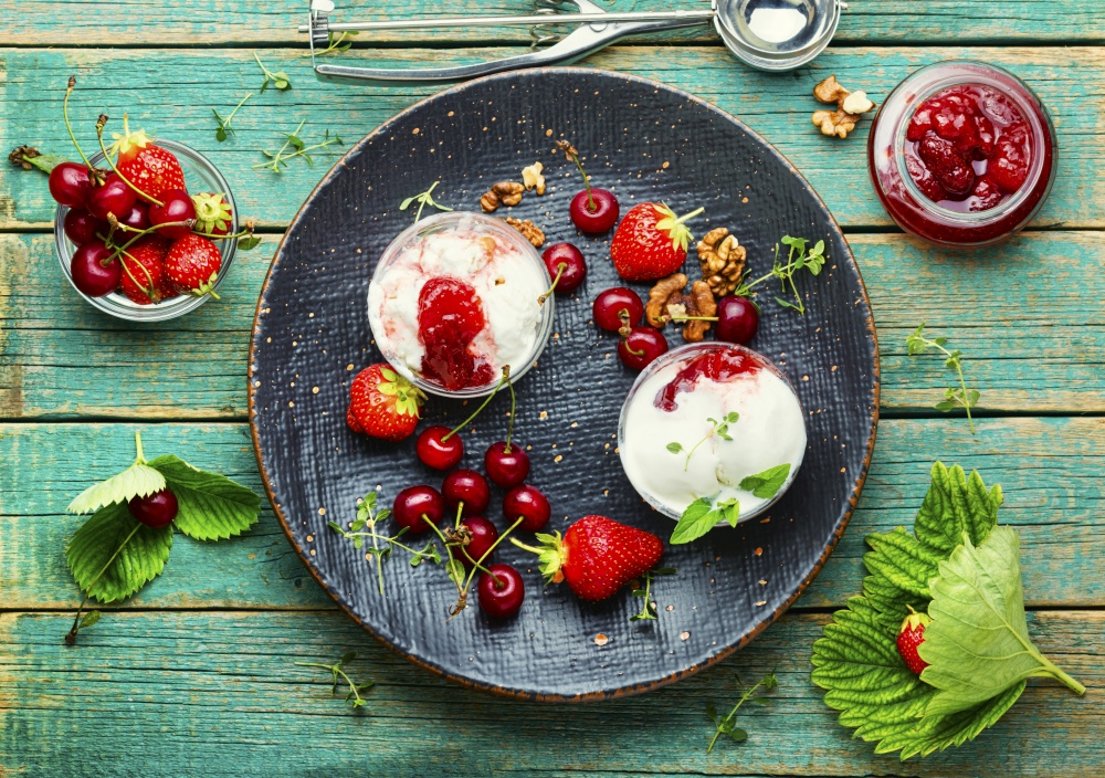 Summer dessert, ice cream with strawberries and cherries.Ice cream with berry jam on wooden table. Tasty ice cream with berries and jam,rustic wooden background