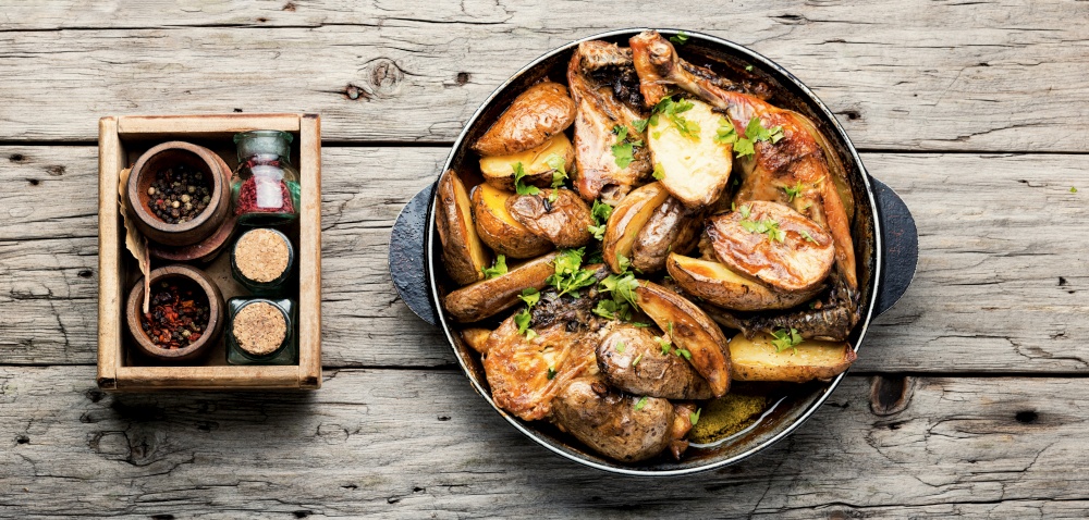 Appetizing chicken meat with potatoes roasted in a pan.Flat lay. Roast chicken leg with potatoes on iron cast pan