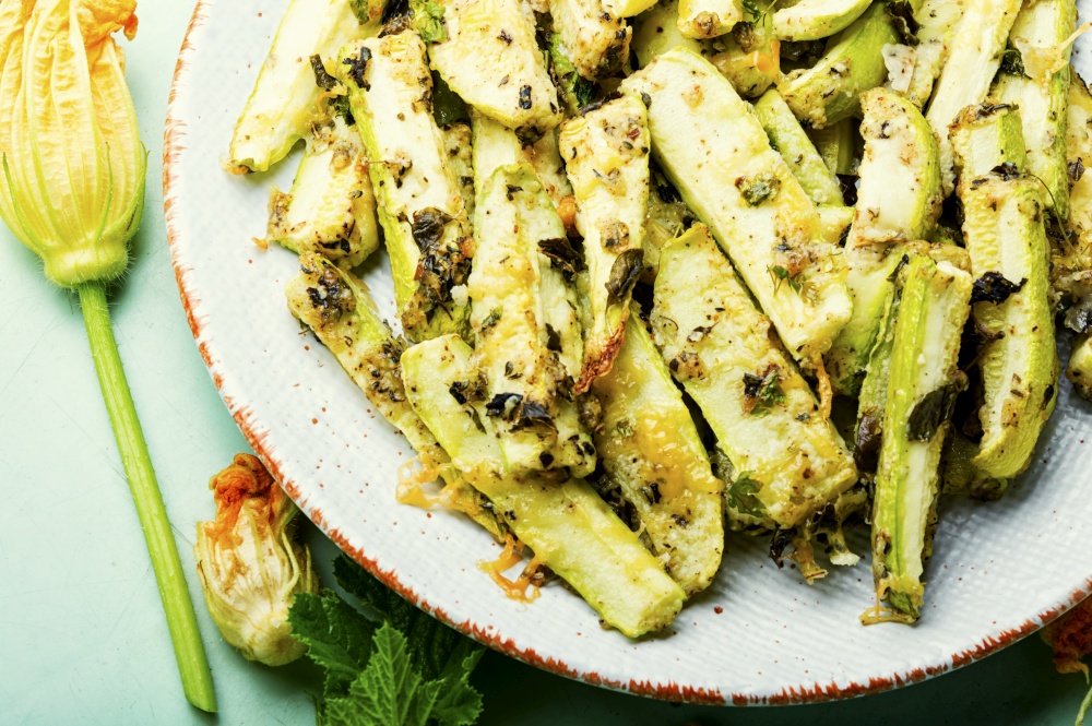 Grilled zucchini with spices and herbs.Roasted zucchini sticks on the plate. Roasted zucchini sticks with greens