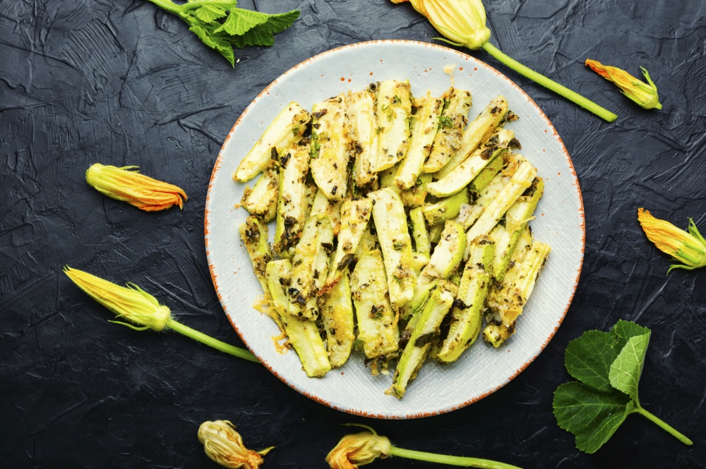 Appetizing homemade baked zucchini with spices and herbs. Roasted zucchini sticks with greens
