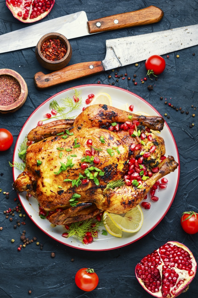 Whole chicken baked with pomegranate.Appetizing meat.Flat lay. Delicious baked chicken on table