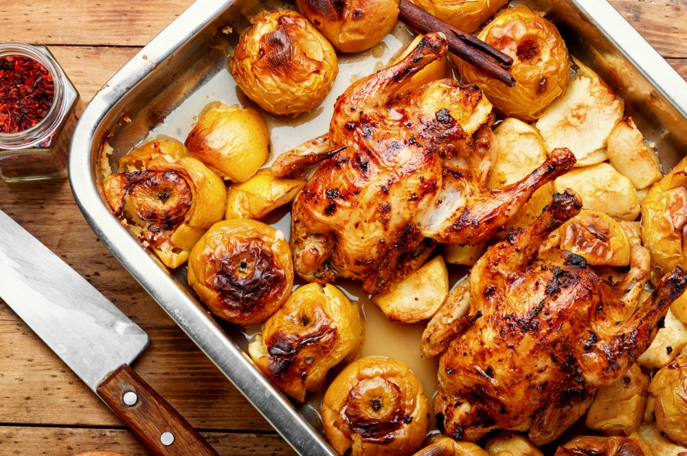 Delicious baked partridge with apples in an iron tray.. Roasted chicken with apples