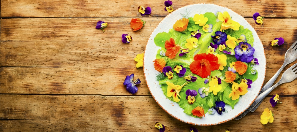 Healthy salad with green lettuce and edible flowers.Fresh summer salad with flowers.Space for text. Edible flower salad in the plate,copy space