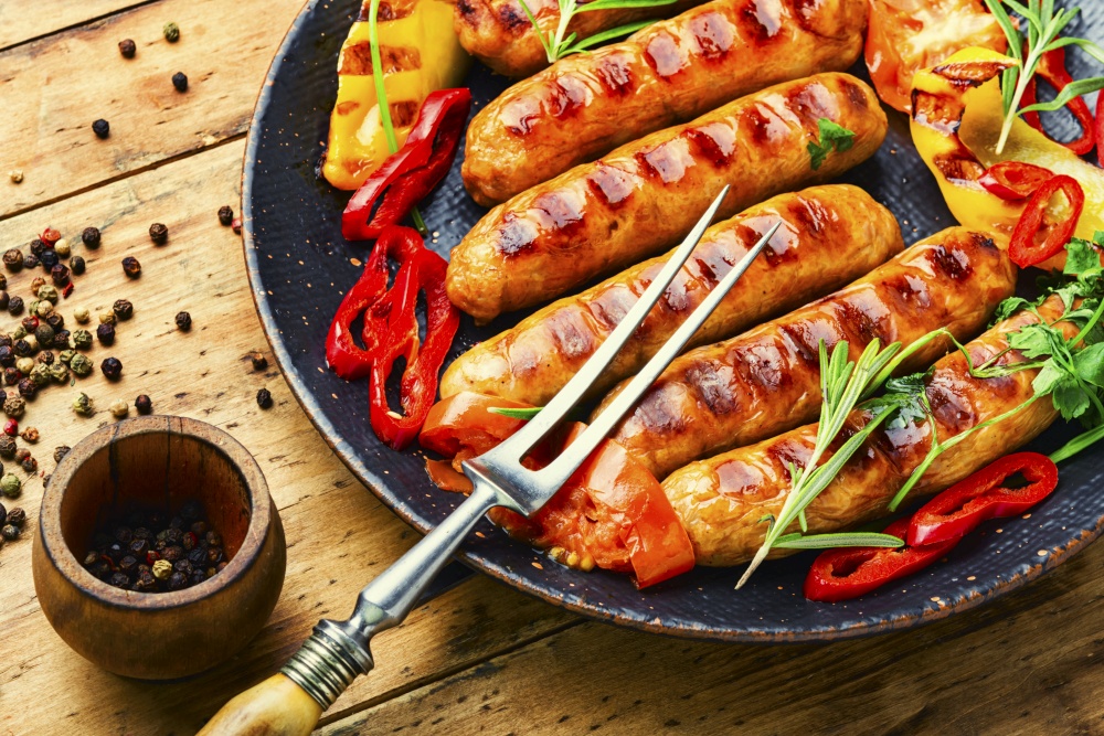 Appetizing grilled sausages with vegetables.Sausages barbecue fried with pepper.. Delicious grilled sausages