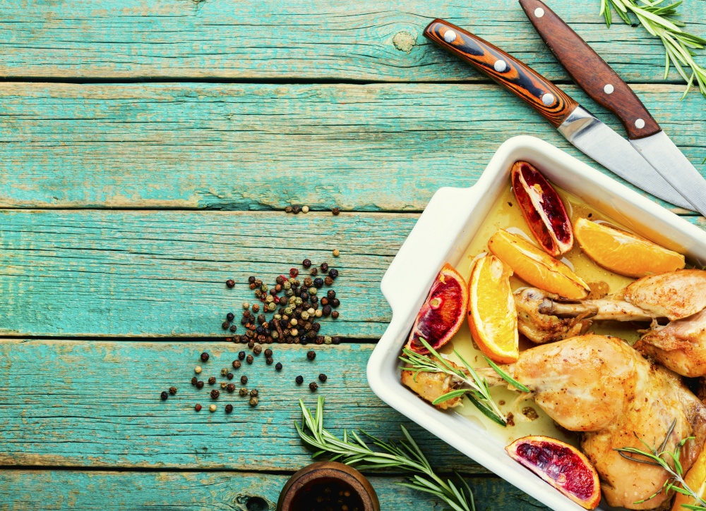 Delicious roasted chicken meat with citrus fruits. Baked chicken legs in a baking dish.Copy space. Baked chicken legs with oranges,space for text