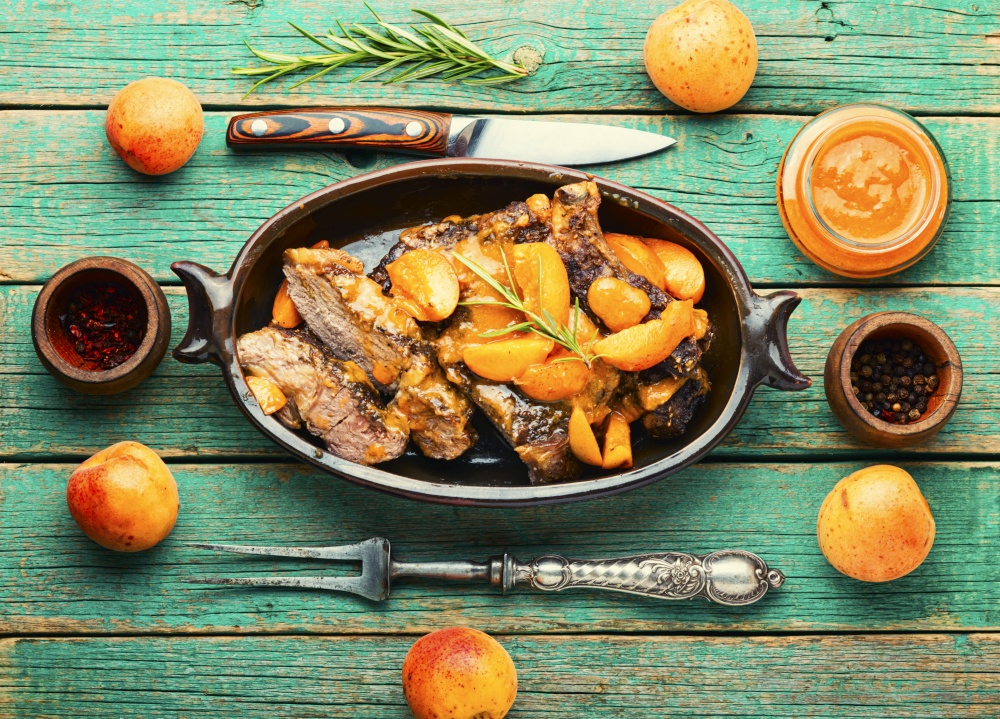 Juicy beef meat in apricot sauce.Veal steak in fruit marinade on old wooden background. Veal steak fried with apricots