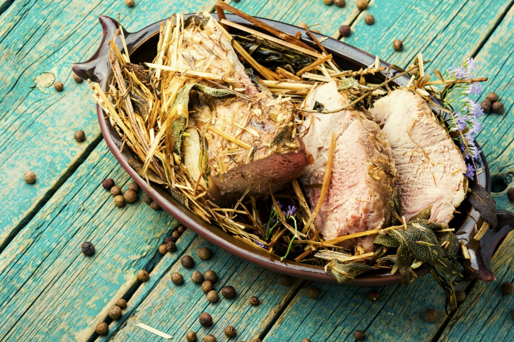 Appetizing meat braised in fresh hay.Roasted pork loin in hays.. Sliced roast in hay, pork roulade