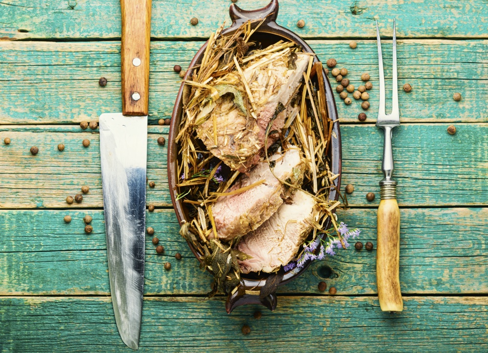 Delicious meat roasted in fresh hay. Baked pork meat in spicy herbs.. Roast pork in hay with herbs