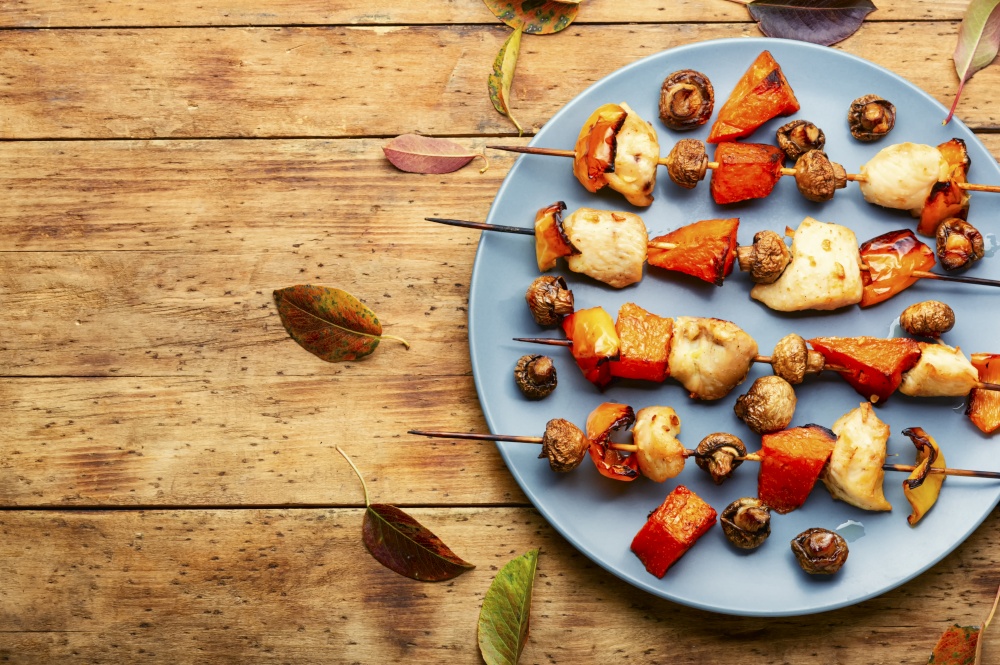 BBQ with chicken, pumpkin and mushrooms on wooden table.Space for text. Skewer with chicken and pumpkin