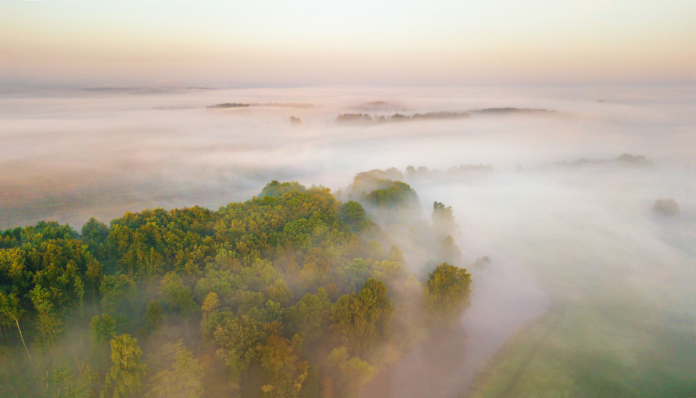 Summer nature landscape aerial panorama. Morning fog over river, meadow and forest. Amazing nature sunlight scene at foggy sunrise. Belarus, Europe