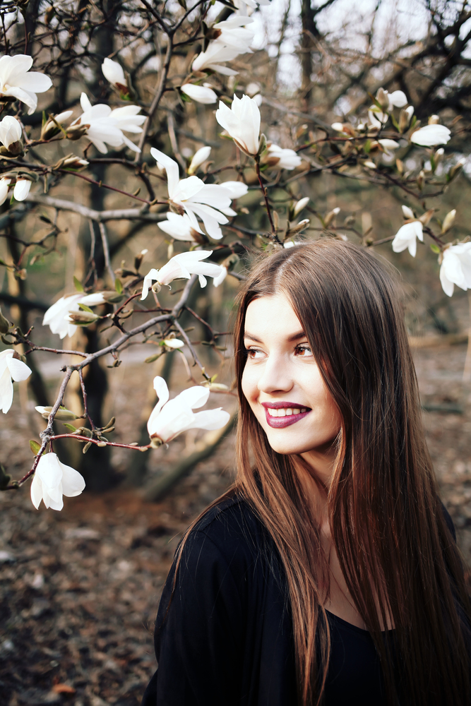 Beauty young woman enjoying nature in spring magnolia flowers.