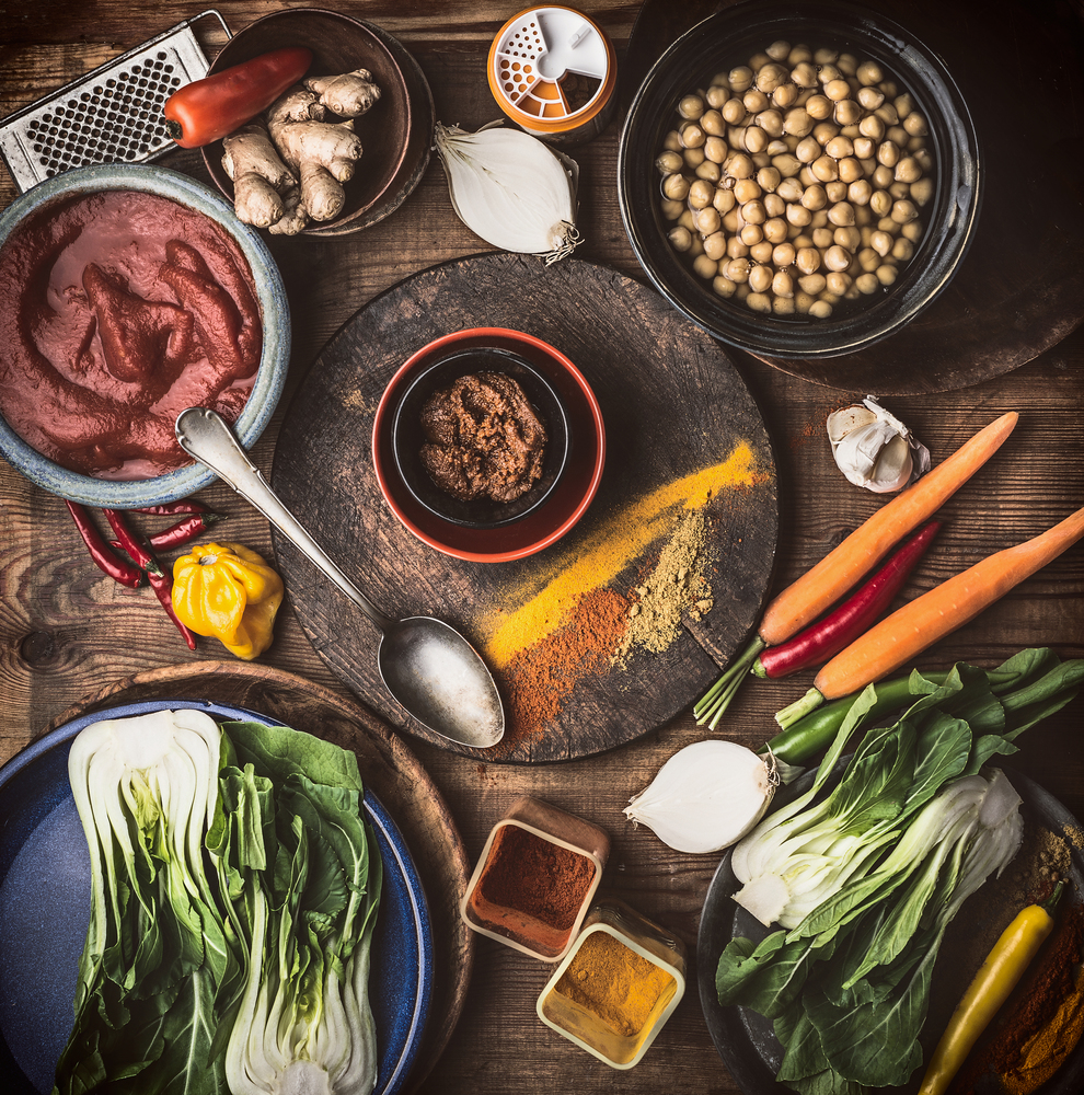 Healthy vegan or vegetarian ingredients : chickpeas , herbs, spices , ginger and  bok choy  on rustic background with cooking spoon, top view, flat lay