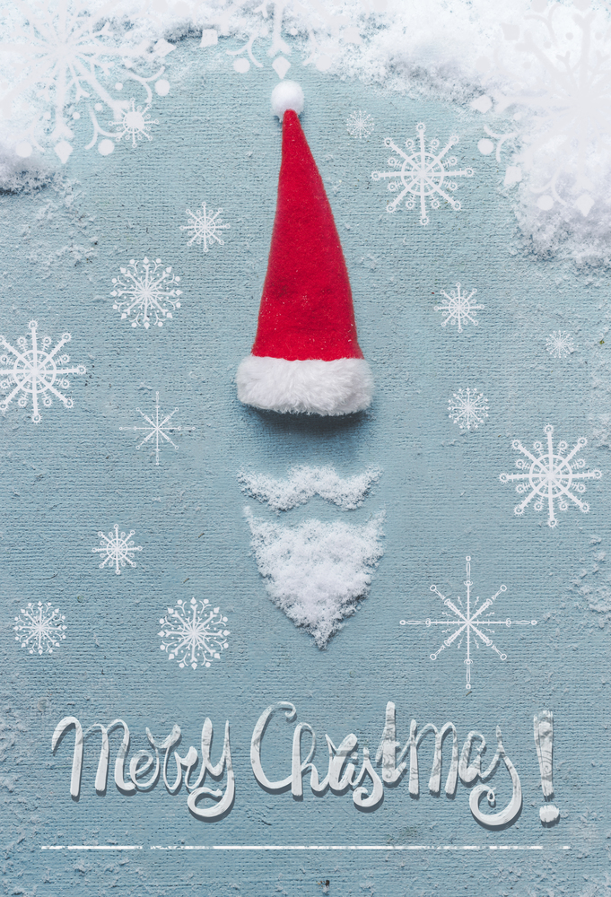 Merry Christmas card with Santa Claus symbol made with snow and Santa hat on blue background. Creative minimal holiday concept