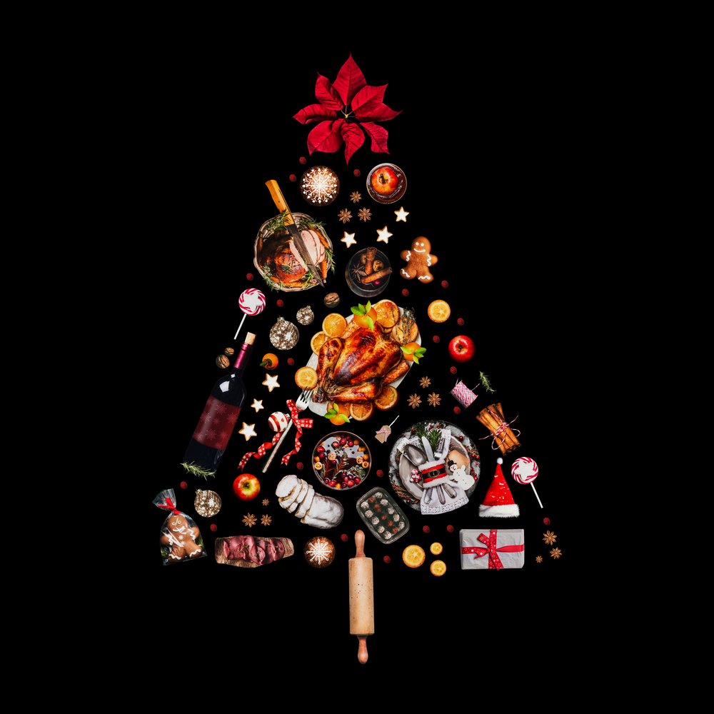 Christmas tree made with various Christmas food: turkey on platter, roasted ham, sweets and candies, cookies , mulled wine, gingerbread  man decorated with gift box and poinsettia. Isolated on black