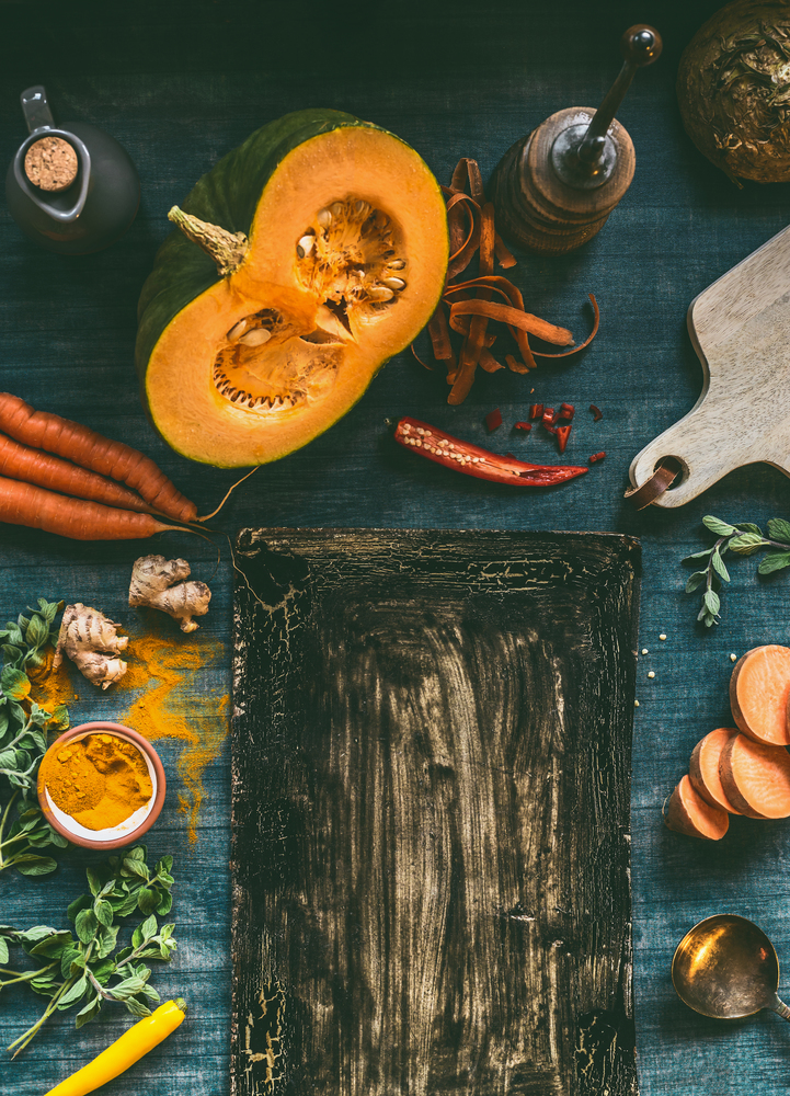 Food background frame with pumpkin and orange color vegetables on kitchen table, top view. Place for your text, design , menu or recipes. Autumn and winter cooking and healthy eating concept.