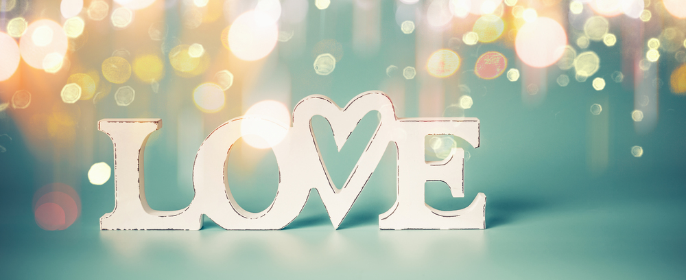 Word love with golden bokeh light on blue background. Valentines day party or abstract love concept