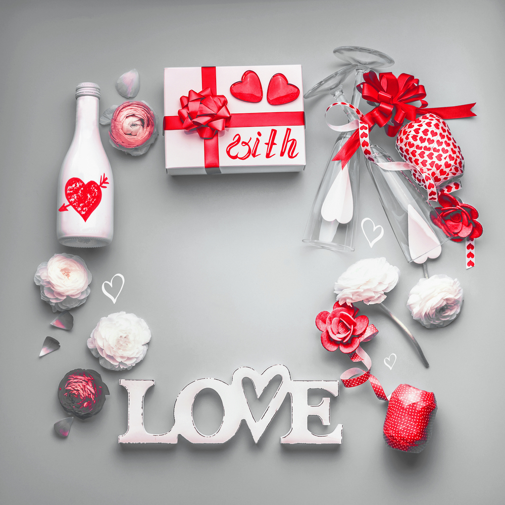 Valentines day background . Festive composition of love made with gift box and red bow, bottle of champagne with glasses, hearts and party accessories. With Love message. Flat lay,  Frame