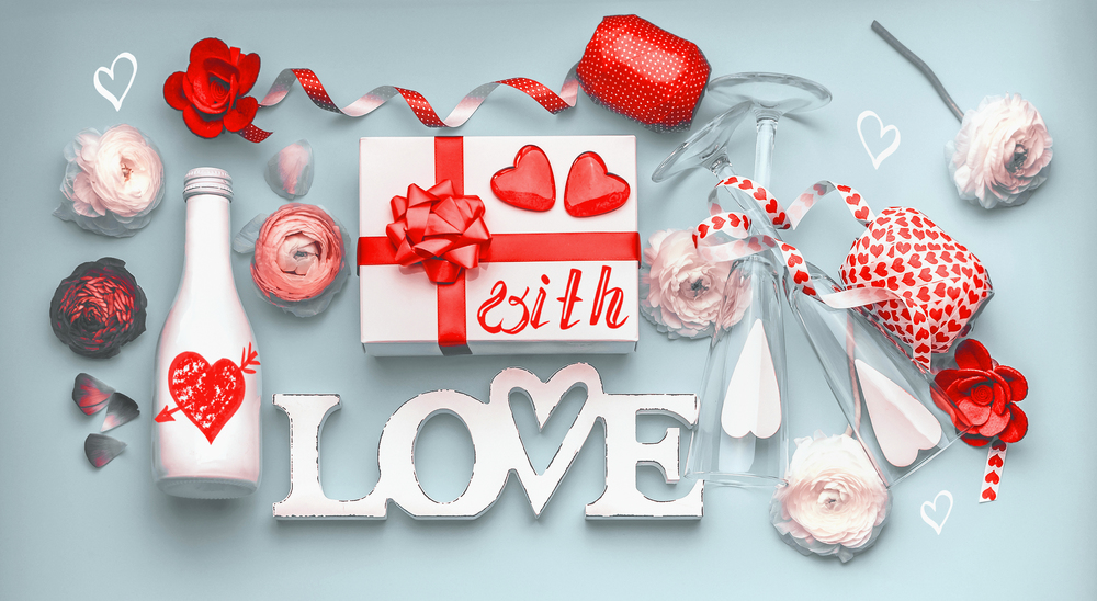 Valentines day layout . Festive composition of love made with flowers, gift box and red bow, bottle of champagne with glasses, hearts and party accessories. With Love message. Flat lay,  Frame
