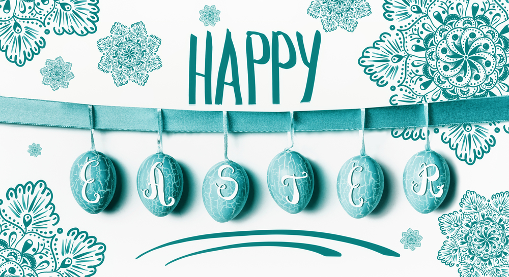 Happy Easter greeting card lettering with hanging turquoise Easter eggs on ribbon with flowers at white wall background