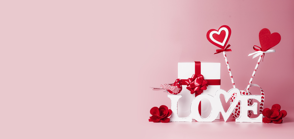 Valentines day background. Word Love, gift box, red ribbons and hearts lollipops. Festive greeting concept. Romantic Love declaration concept. Copy space for your design. Banner.