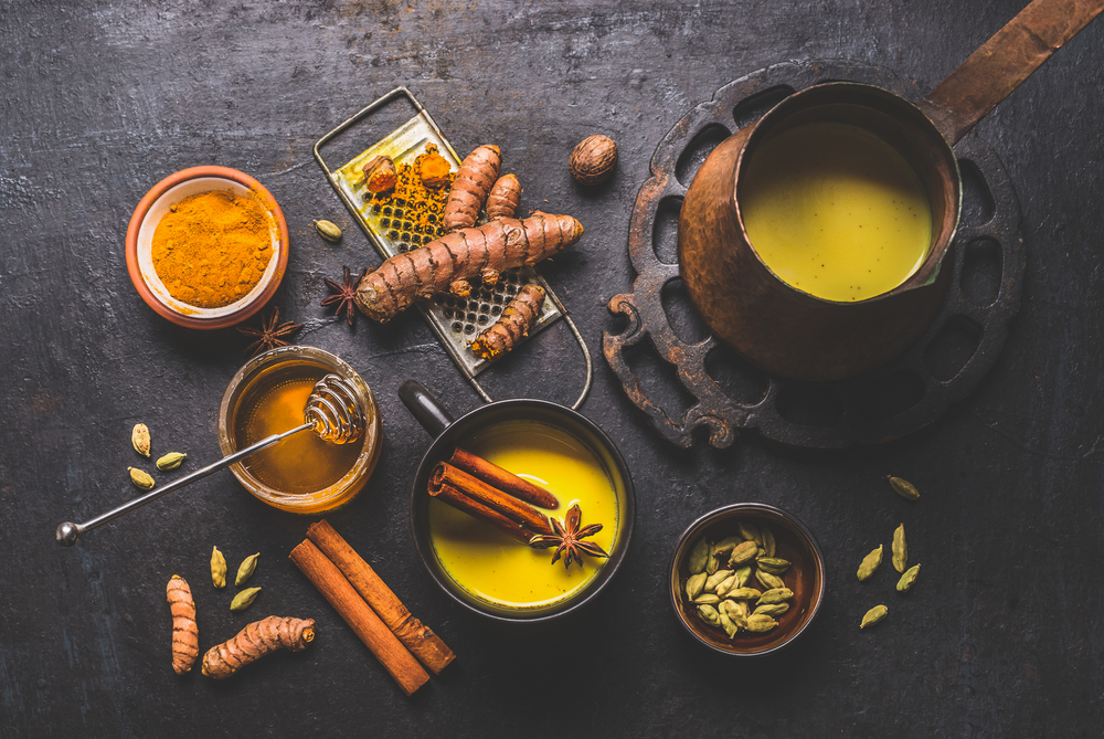 Healthy ingredients of turmeric milk drink with fresh turmeric roots , spices and honey. Hot winter beverage. Immune boosting remedy , detox and dieting concept