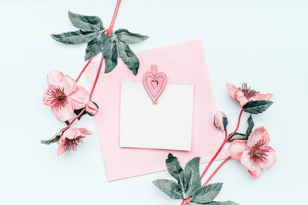 Greeting card mock up with pastel pink heart and flowers on white background , top view, frame Flat lay. Can using to Mothers day, wedding, birthday, Valentines day