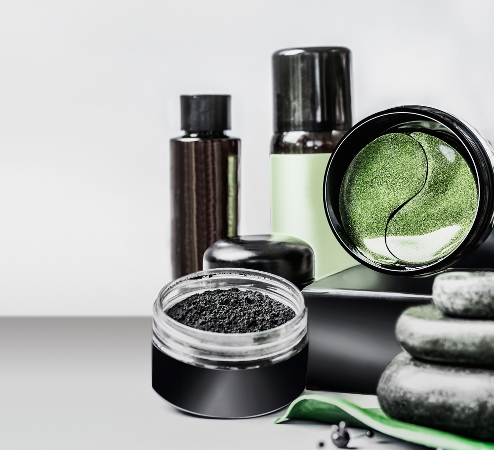 Cosmetics setting ads. Black package template with charcoal powder and green eye patches . Branding mock up. Charcoal cosmetic set. Facial skin care . Beauty blog promotion. Cosmetic store .