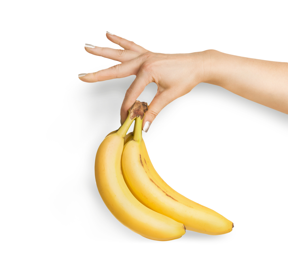 Bunch of organic bananas in female hand at white background. Isolated. Summer tropical fruits concept. Copy space for your design
