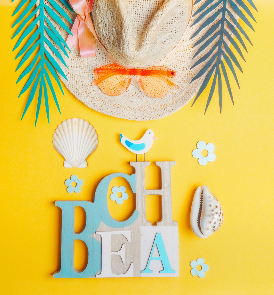 Summer beach accessories. Straw hat with sunglasses , sea shells and tropical leaves on yellow background, top view. Summer holiday concept. Tropical vacation . Flat lay