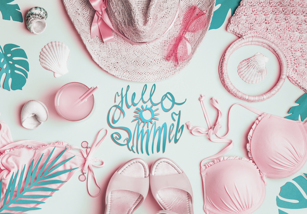 Pastel girls beach accessories: bikini, straw hat, sunglasses, sandals , cocktail drink , seashells , tropical palm leaves. Summer female fashion outfit. Top view. Hello Summer text lettering