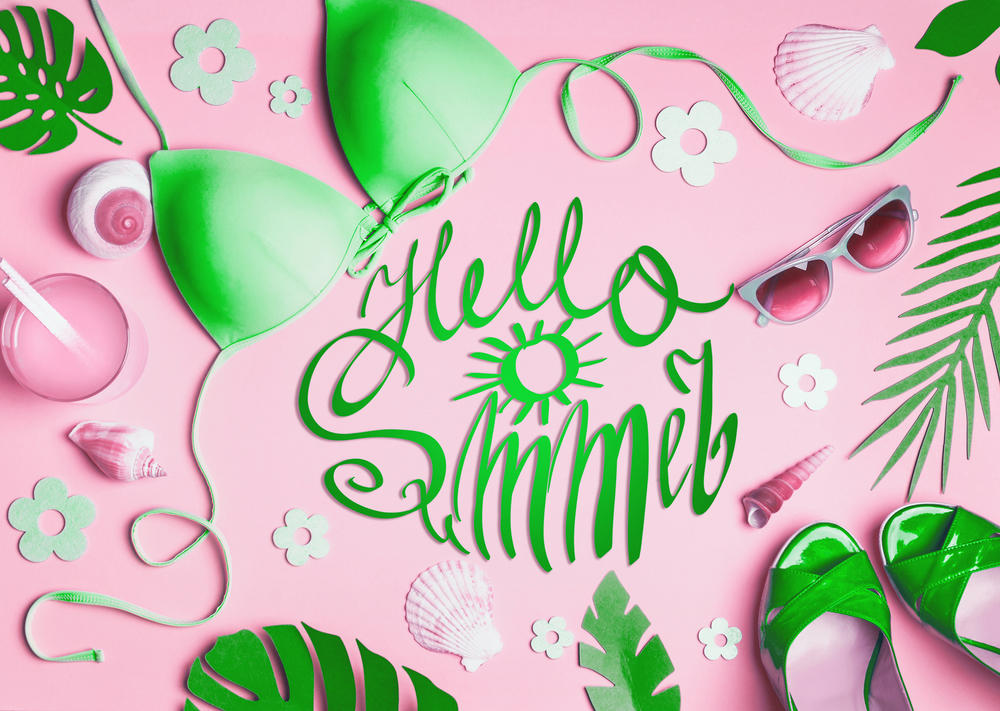 Hello summer. Female beach accessories on pink background, top view. Flat lay green bikini, sunglasses, sandals with cocktail , seashells , tropical palm leaves. Summer holiday vacation layout.