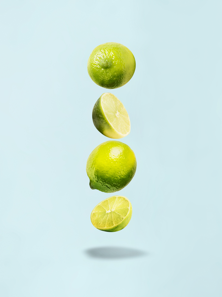 Flying lime on blue background with shadow. Healthy food.