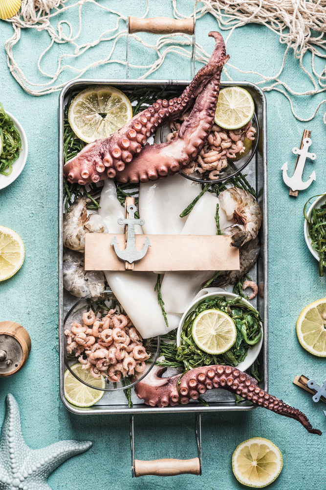 Various seafood on tray with blank sign and anchor, top view.  Healthy seafood cooking
