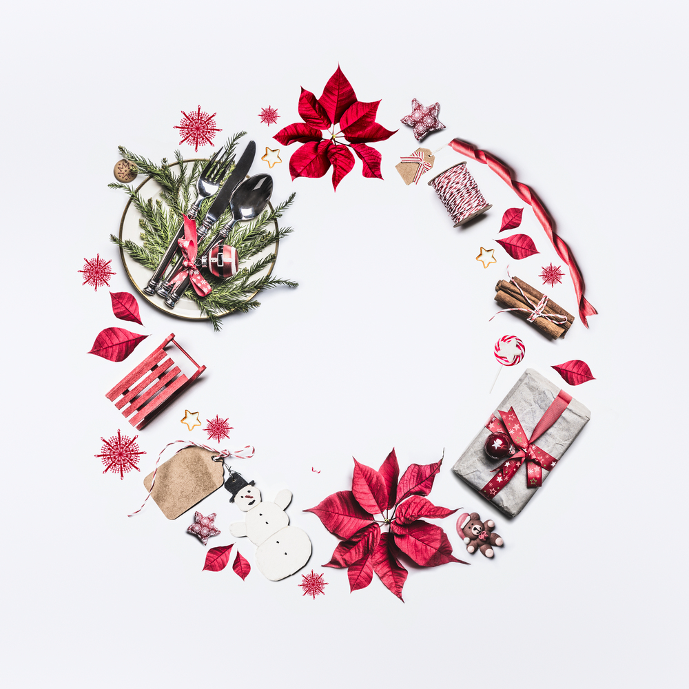 Christmas frame composition made with festive decoration objects lake Christmas wreath on white background , top view. Flat lay. Festive  layout with poinsettia, gift box, festive table setting
