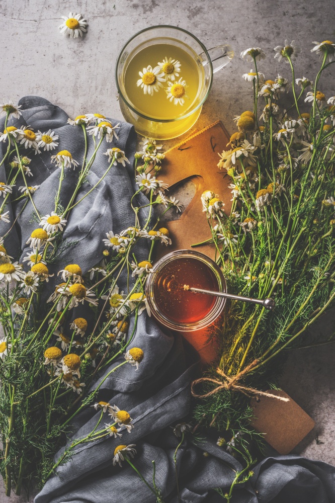 Herbal tea in glass cup with honey and  fresh medicinal plants. Dark concrete background with dark cloth. Top view. Natural health drinks concept