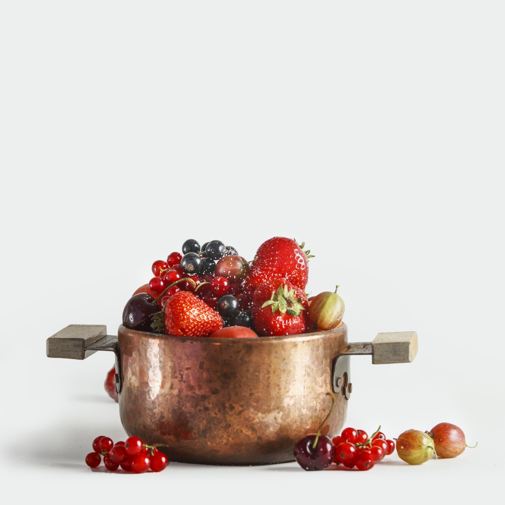 Copper cooking pot with fresh fruits and berries st white background
