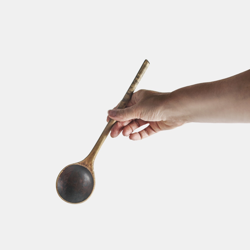 Women hand holding wooden spoon at white background
