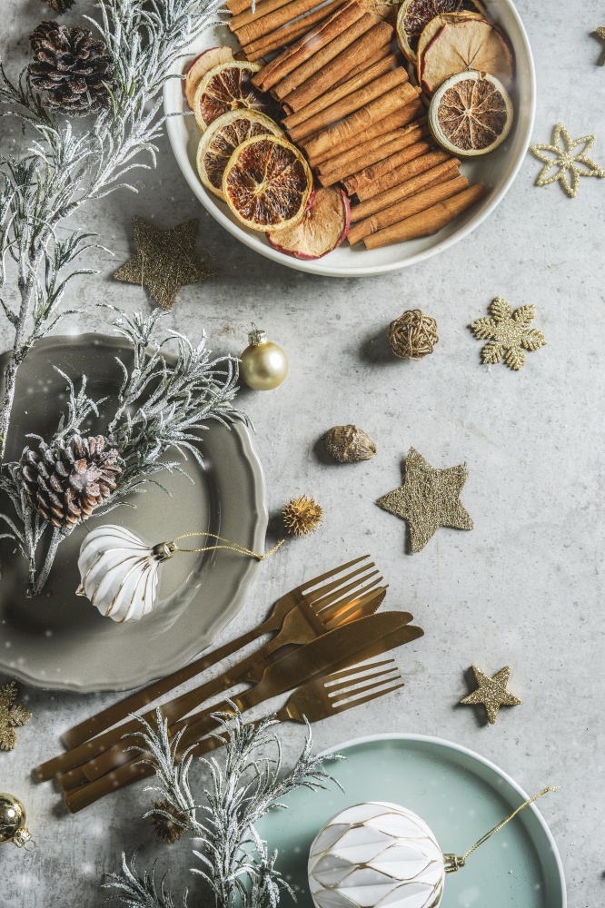 Christmas table setting with decoration, plates, cutlery and winter spices: cinnamon sticks, anise stars and dried orange slices, top view