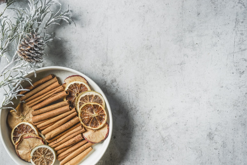 Plate with winter spices: cinnamon sticks, anise stars and dried orange slices, top view