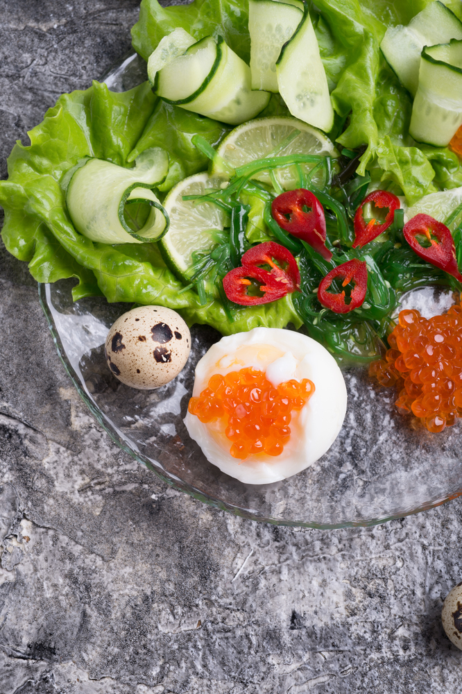 fresh  gourmet salad with  red  salmon caviar and chuka,  eggs and vegetables. close up.  Protein luxury delicacy  healthy food. flat lay