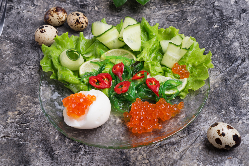 fresh  gourmet salad with  red  salmon caviar and chuka,  eggs and vegetables. close up.  Protein luxury delicacy  healthy food.