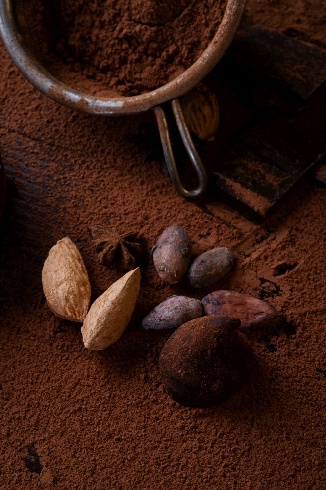 art background with healthy delicious dark truffles, chocolate  and  ingridients:  natural cocoa beans,  powder, chocolate, almonds  nuts and  ripe cherry. healthy sweets concept.