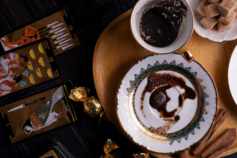 spelling coffee plate  with  coffee grounds and Tarot cards served at dark wooden table. devination concept . flat lay. close up